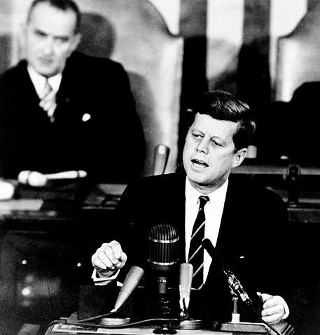 Pressé par les rapports alarmants de la CIA sur le programme spatial soviétique, Kennedy lance le 25 mai 61 la course à la lune. Son vice-président (derrière à gauche), s’il ne paraît pas convaincu, sait déjà qu’il en tirera gloire et….des subsides pour son état, le Texas (Houston devient le fief de la NASA, créée en 1960 par Eisenhower).